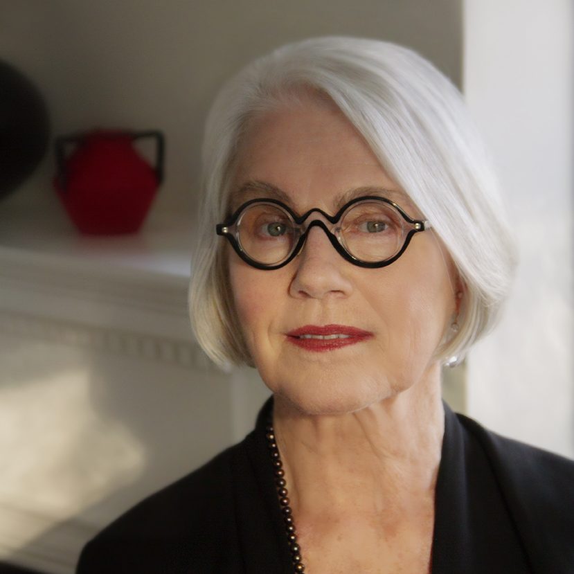 Rosemarie Garland-Thomson is a white woman with silver hair cut in a bob. She wears red lipstick and black, circle-rimmed glasses.