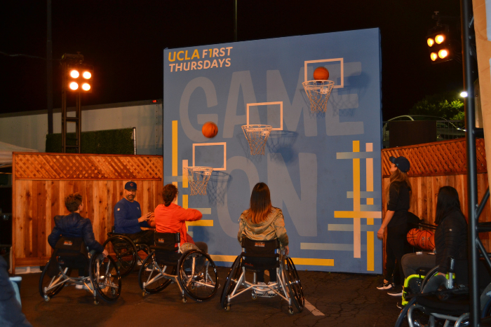 Pictured are First Thursdays attendees playing wheelchair basketball and shooting hoops together. Games were played throughout the night, led in partnership by members of PlayLA and UCLA Adaptive Rec.