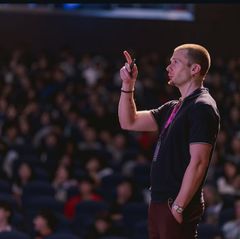 Russell Lehmann at a speaking engagement pointing towards the ceiling.