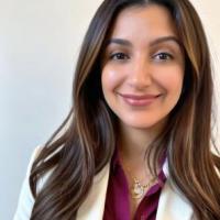 Yasamin Bolourian, a long brown haired woman smiling, wearing a purple shirt and white blazer.