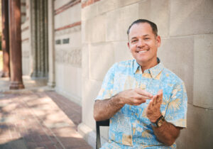 Image of Benjamin Lewis signing the word "integrity" in front of Powell Library.